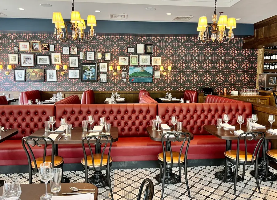 Barsotti’s dining room with red tufted booths, chandeliers, and a gallery wall