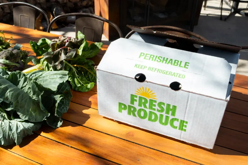 A fresh-produce box and just-picked greens on a table at the Bonton Farms market