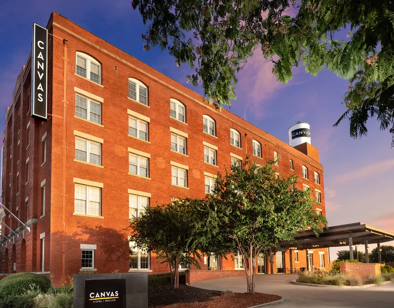 The red-brick CANVAS Hotel and its rooftop water tower at dusk
