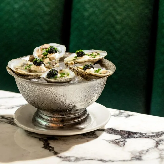 A silver bowl of chargrilled oysters on a marble table at Green Point Seafood & Oyster Bar