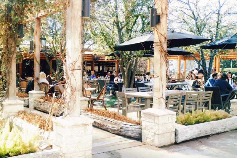 The tree-shaded patio at Smoky Rose, set with tables under black umbrellas
