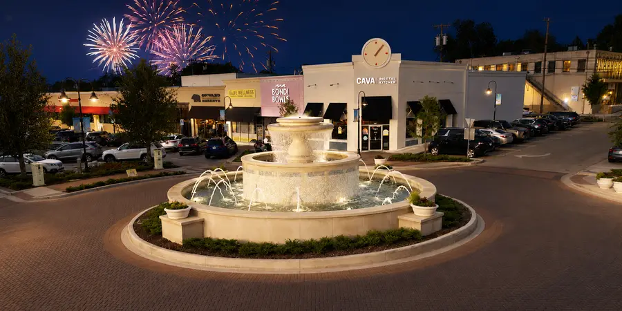 The Snider Plaza fountain at dusk with fireworks over the shops