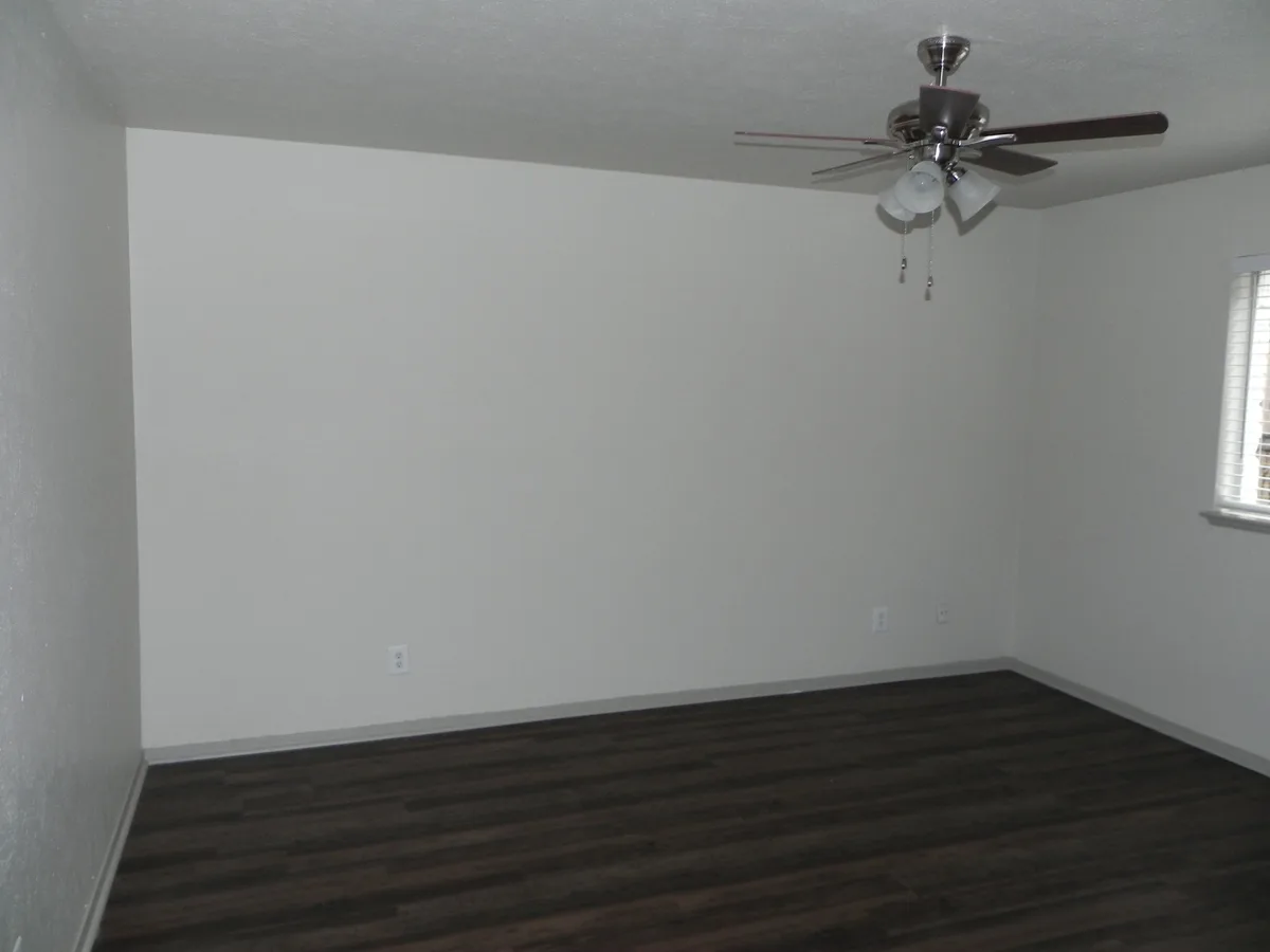 Bedroom with ceiling fan, corner window and dark wood-look flooring
