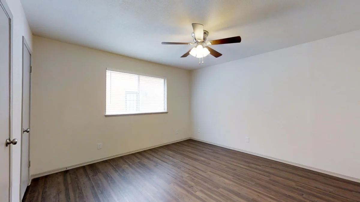 Bedroom with ceiling fan, window and closet door over wood-look flooring