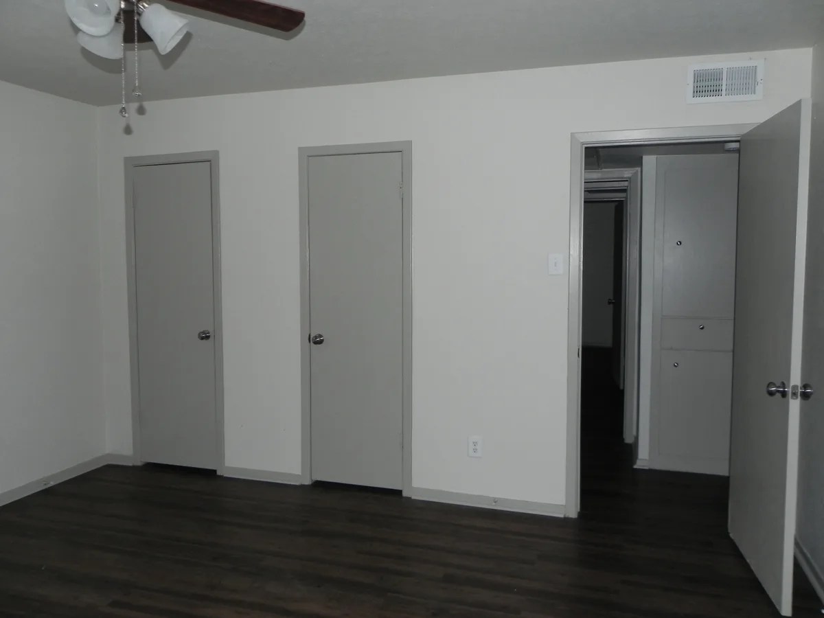 Bedroom with two closet doors and hallway access in wood-look flooring