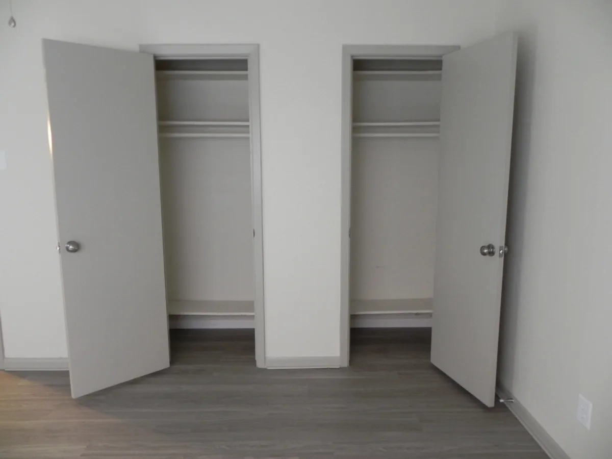 Two side-by-side reach-in closets with shelving and hanging rods, doors open