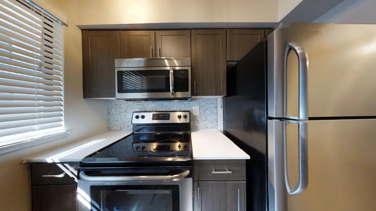 Kitchen with white shaker cabinets, dark countertops and marble mosaic backsplash
