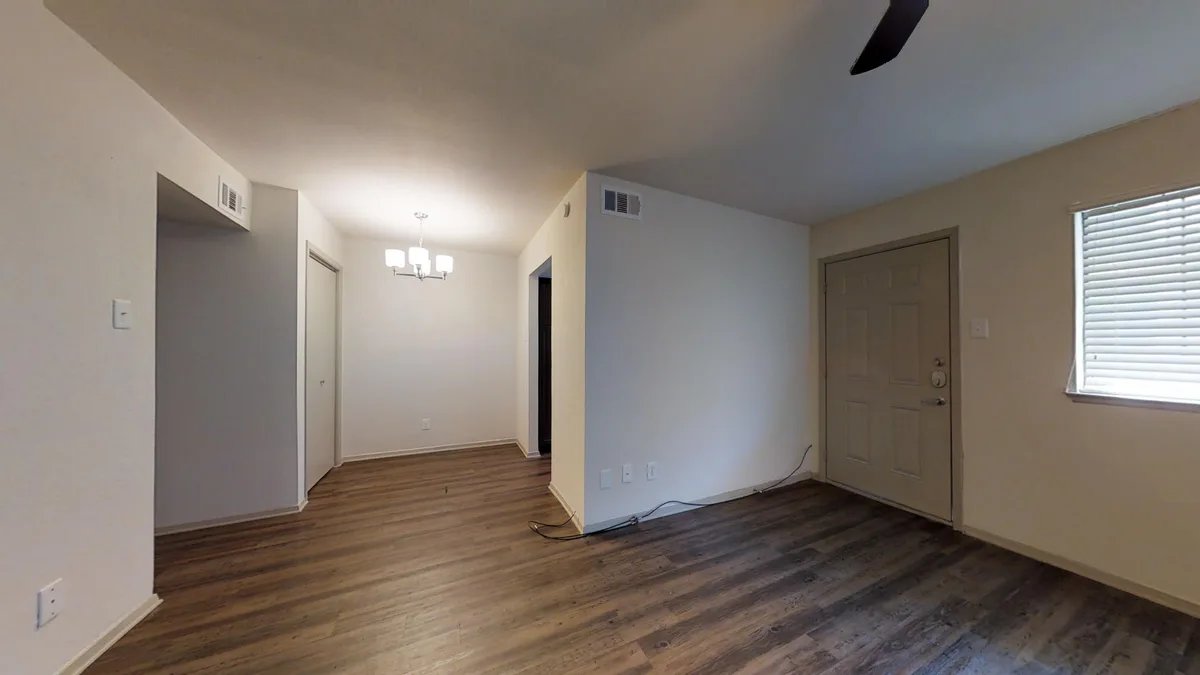 Open living and dining room with ceiling fan, front entry and wood-look floors
