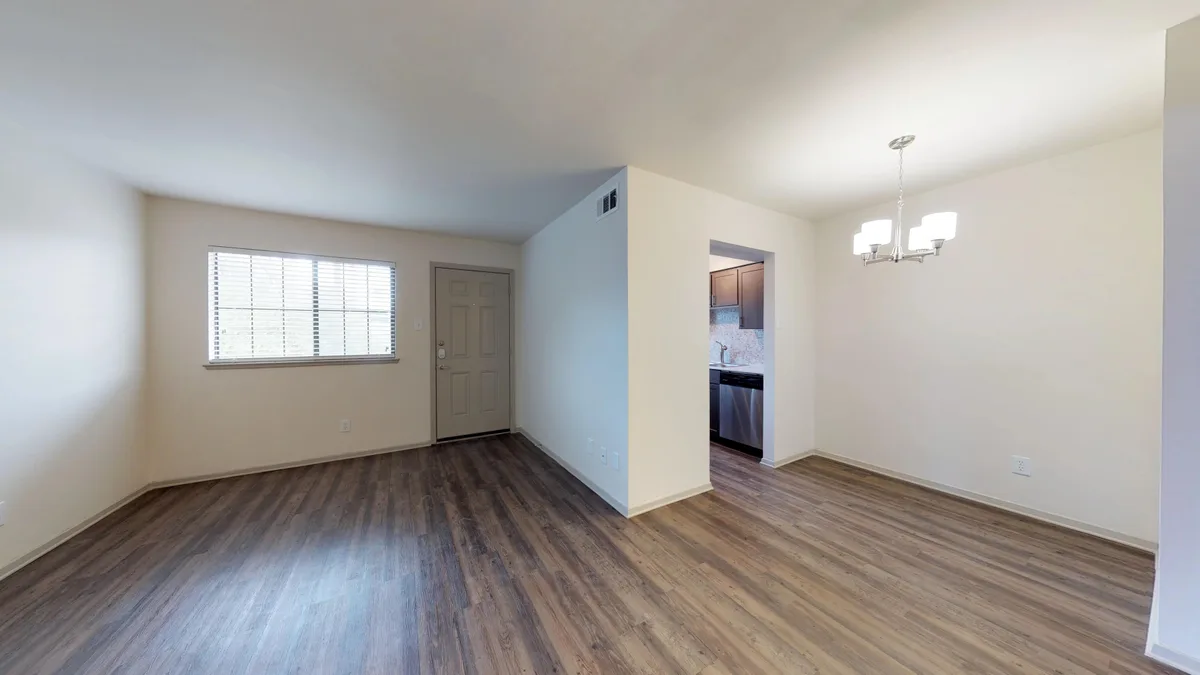 Spacious living room with front door, picture window and view into the kitchen