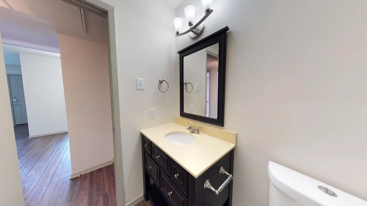 Bathroom vanity with espresso cabinet, framed mirror and view toward the living room