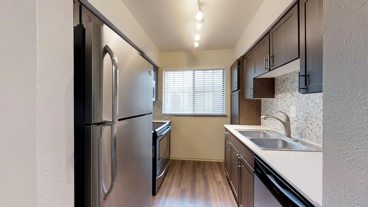 Galley kitchen with stainless appliances, espresso cabinets and bright window over double sink