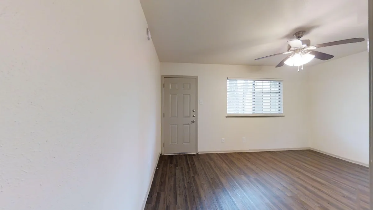 Living room with ceiling fan, front entry door and natural light from window