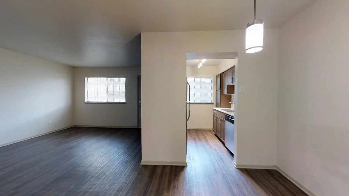 Open living and dining area with pendant light and pass-through to galley kitchen