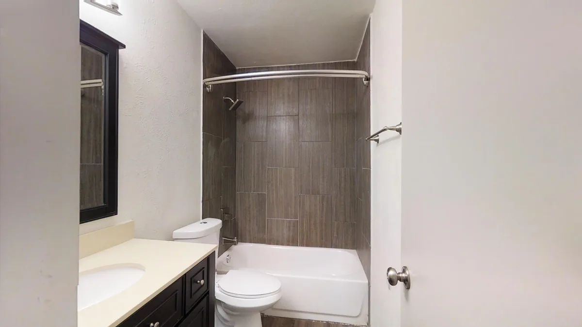 Bathroom with dark vanity, cream counter and gray-tiled tub-and-shower surround