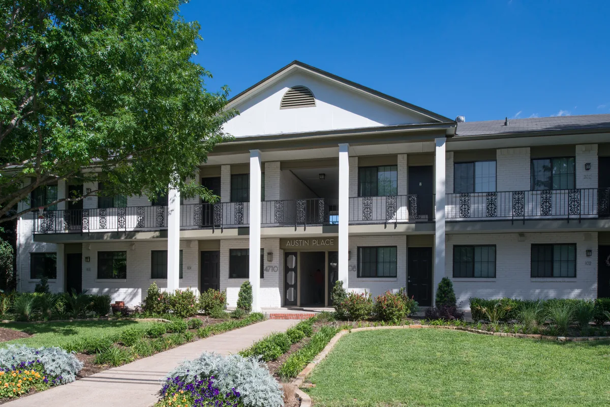 Two-story white-painted brick building with columned entry portico and manicured front lawn