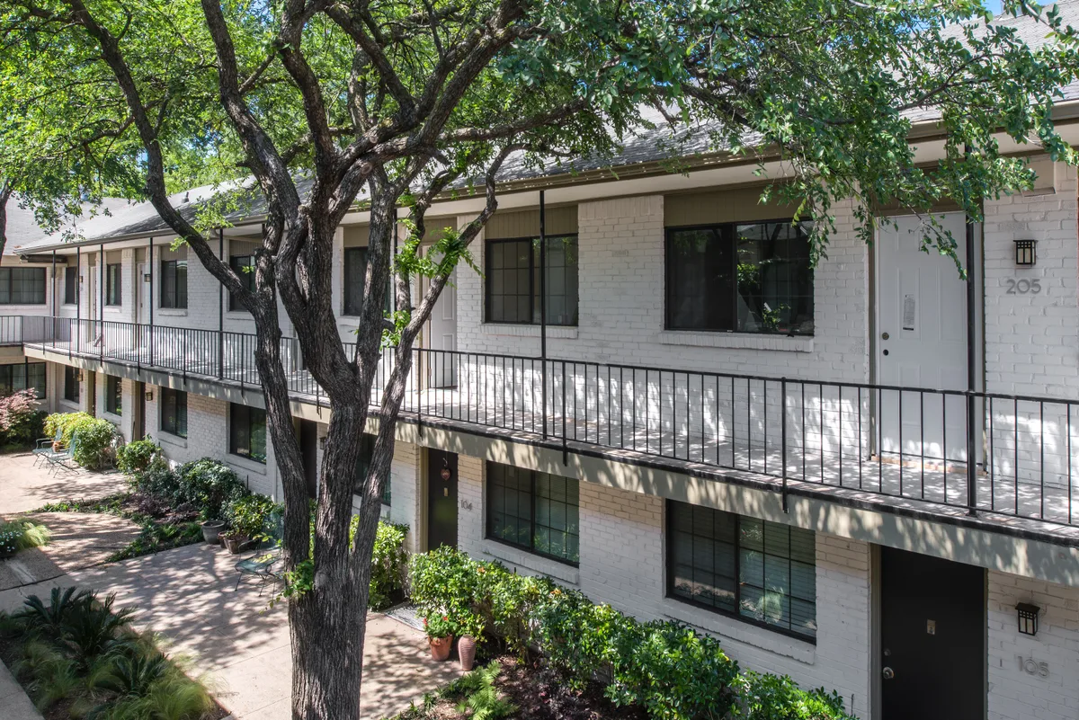 Landscaped interior courtyard with second-floor balcony walkway and mature shade trees