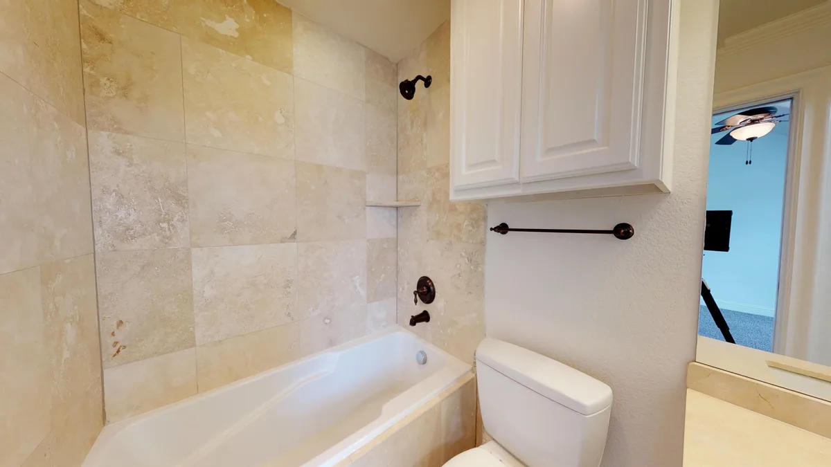 Bathroom with a travertine-tiled tub and shower combination and an oil-rubbed bronze fixture