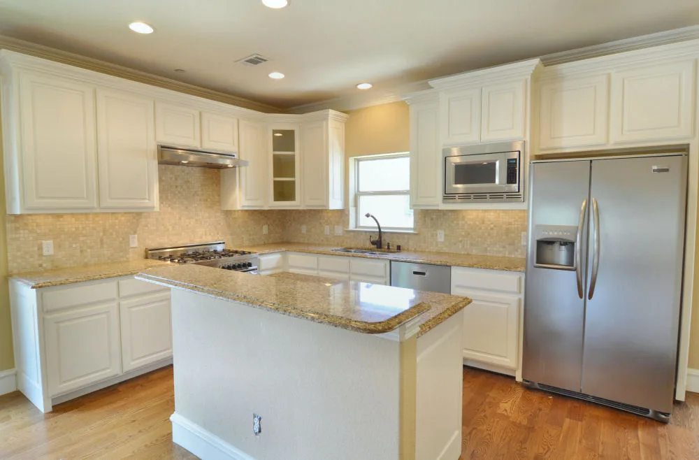 Kitchen with granite center island, white cabinetry, and stainless side-by-side refrigerator