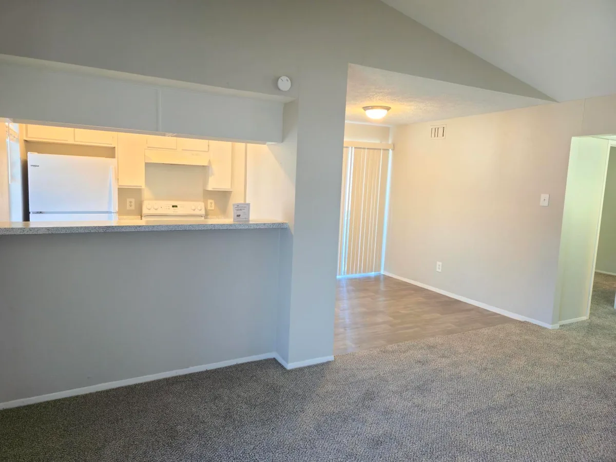 Breakfast bar opening from the kitchen to the vaulted living and dining room