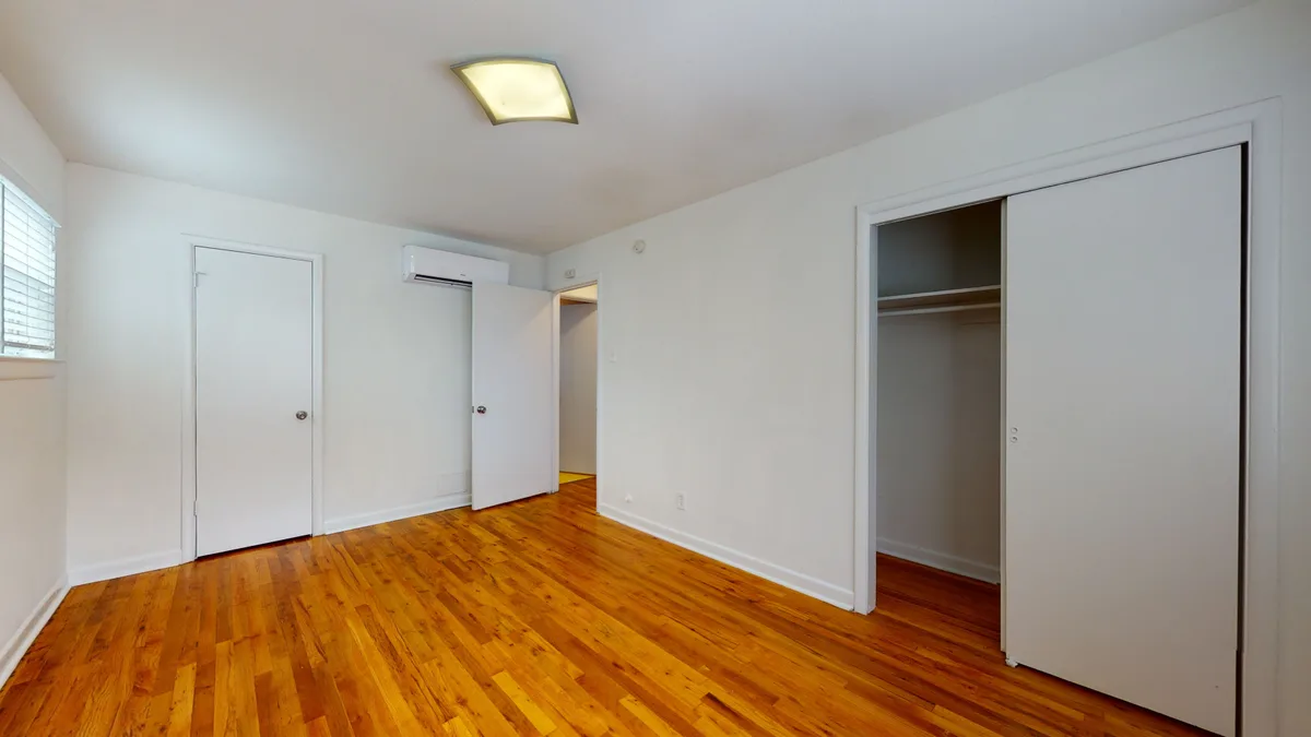 Bedroom with hardwood floors, ductless mini-split and a sliding-door reach-in closet