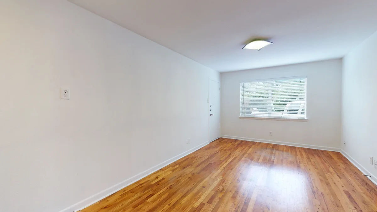Bedroom with refinished red-oak hardwood floors and a bright blinded window