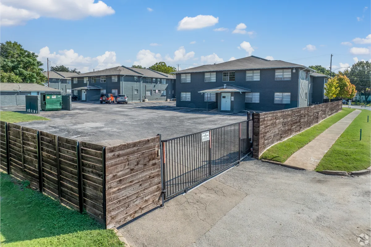 Gated off-street parking lot enclosed by wood privacy fencing beside the residential buildings
