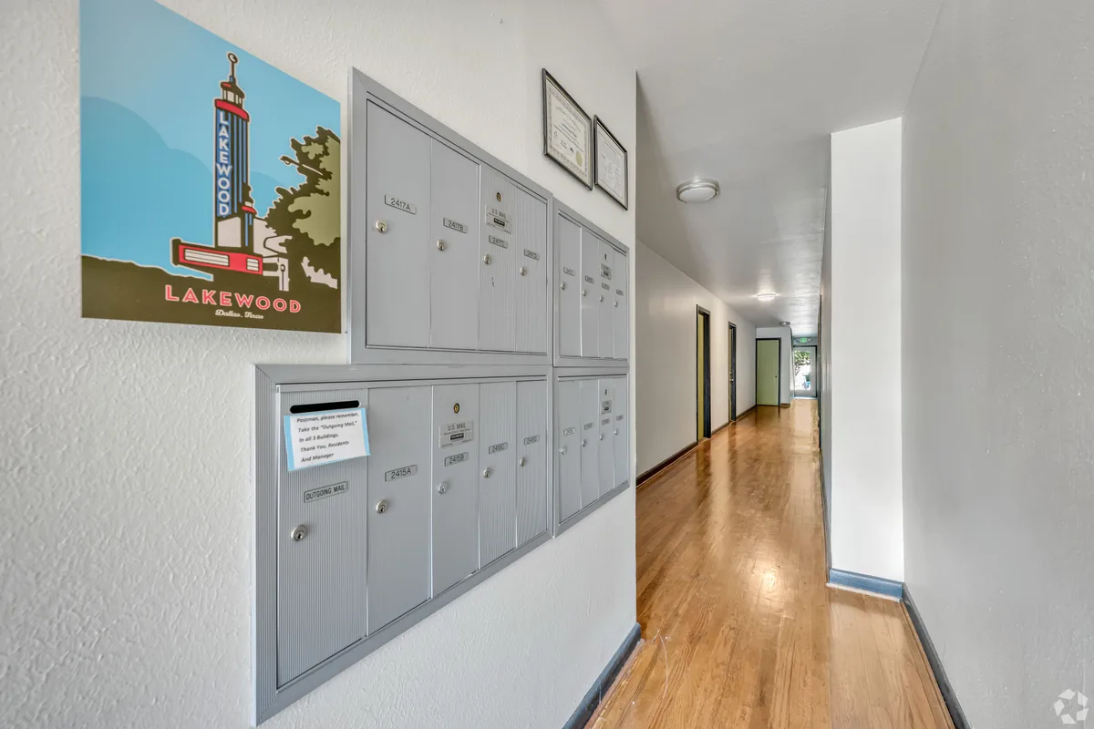 Interior mail room with grouped resident mailboxes and a vintage Lakewood print above hardwood hallway