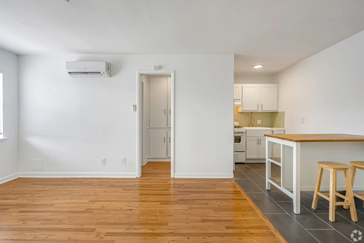 Open living space with mini-split, butcher-block island and wood bar stools beside the kitchen