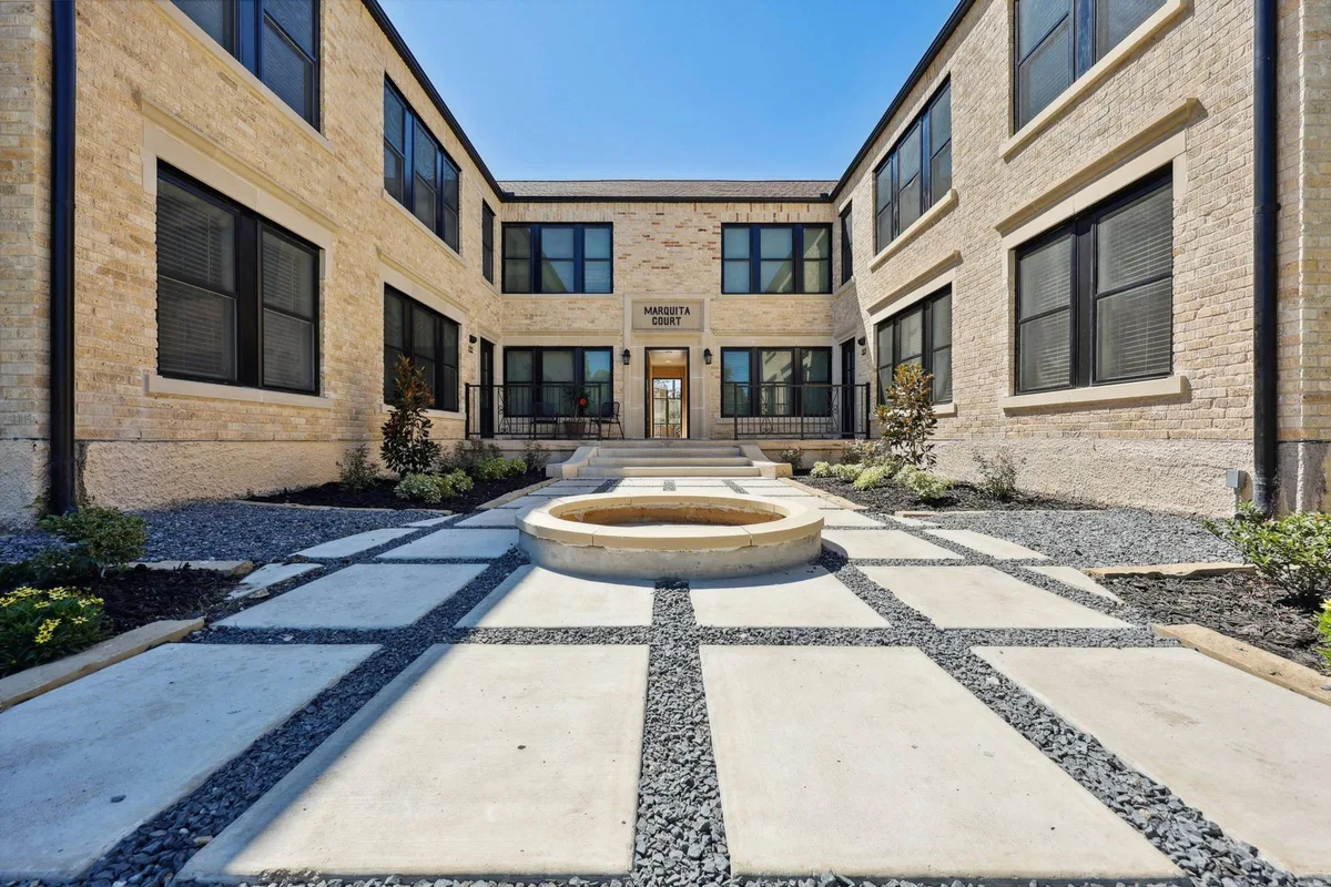 Interior courtyard with a round stone fountain, checkerboard concrete-and-gravel paving, and the Marquita Court entrance
