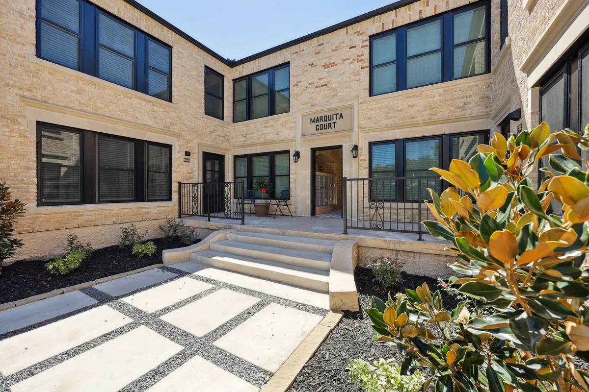 Landscaped courtyard entrance with limestone steps, iron rails, and the cast 'Marquita Court' name over the door