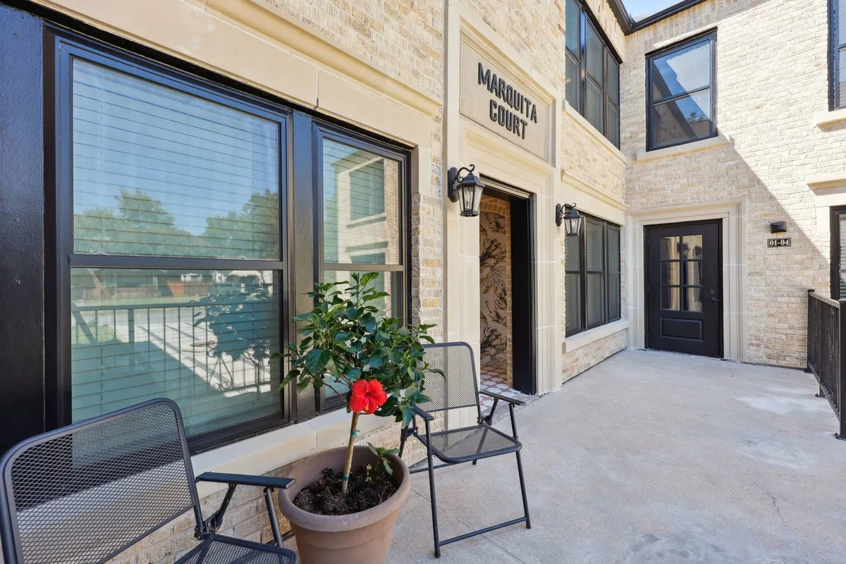 Shared front-porch patio with black bistro chairs and a potted hibiscus beside the main entrance