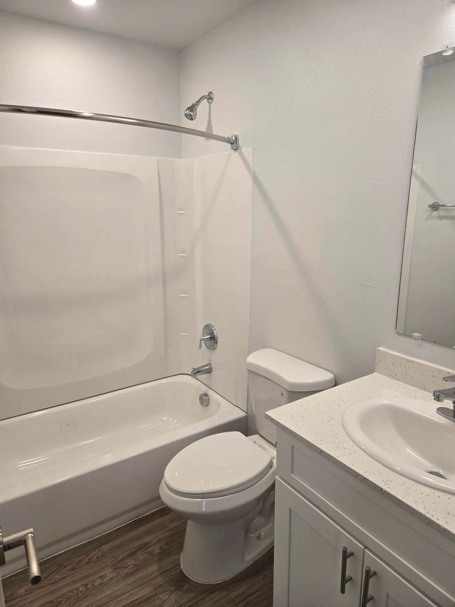 Bathroom with a tub and shower combo, toilet and a speckled white countertop vanity cabinet