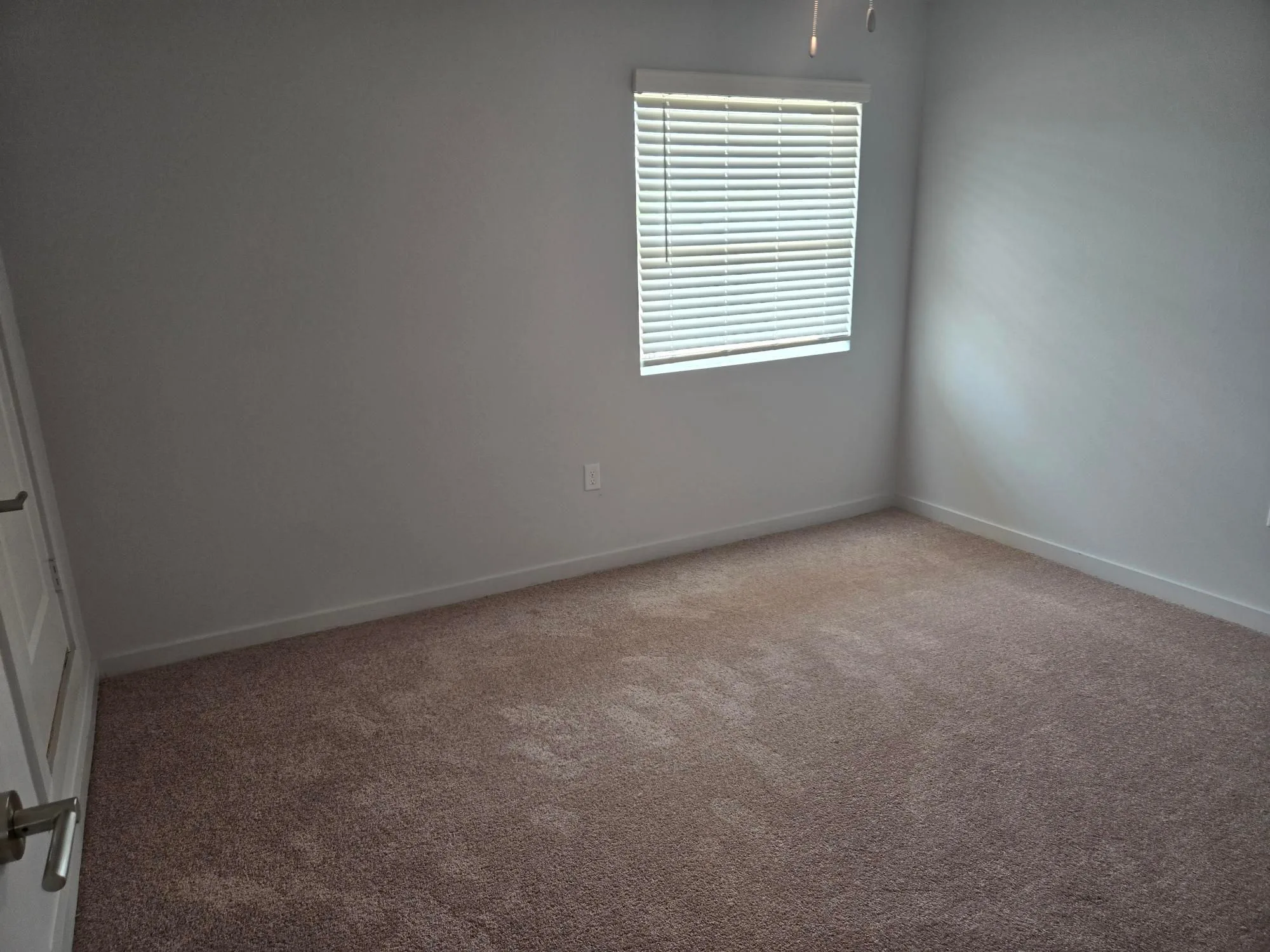 Second carpeted bedroom with neutral gray walls, a window with blinds and closet access
