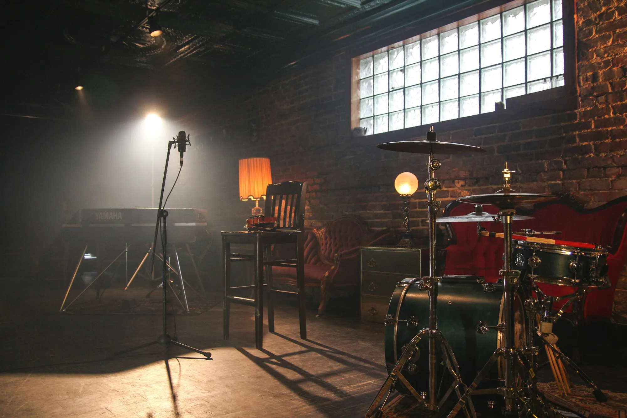 Drum kit and microphone lit on a brick-walled live music stage at a nearby downtown venue