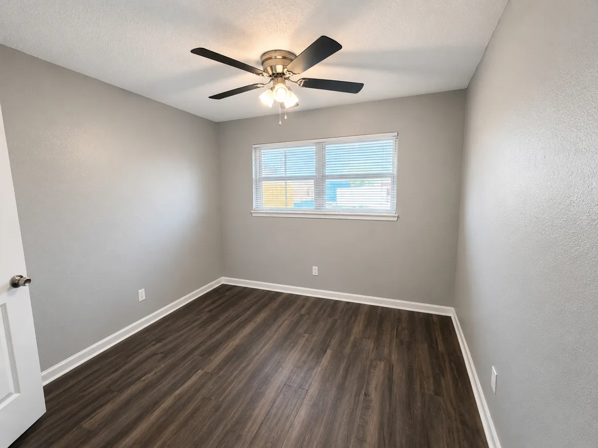 Bedroom with ceiling fan, blinded window, and dark wood-look plank flooring
