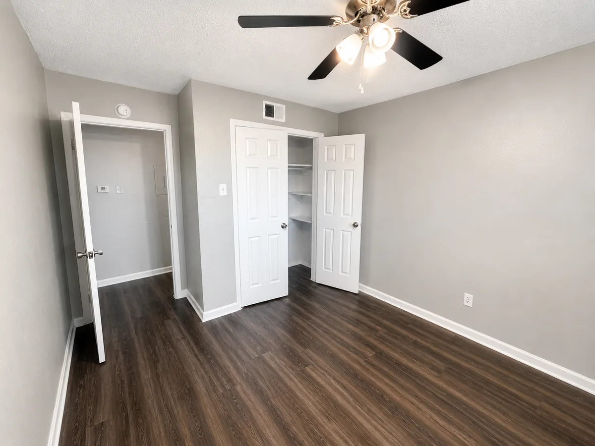 Bedroom with ceiling fan and open reach-in closet showing built-in shelving