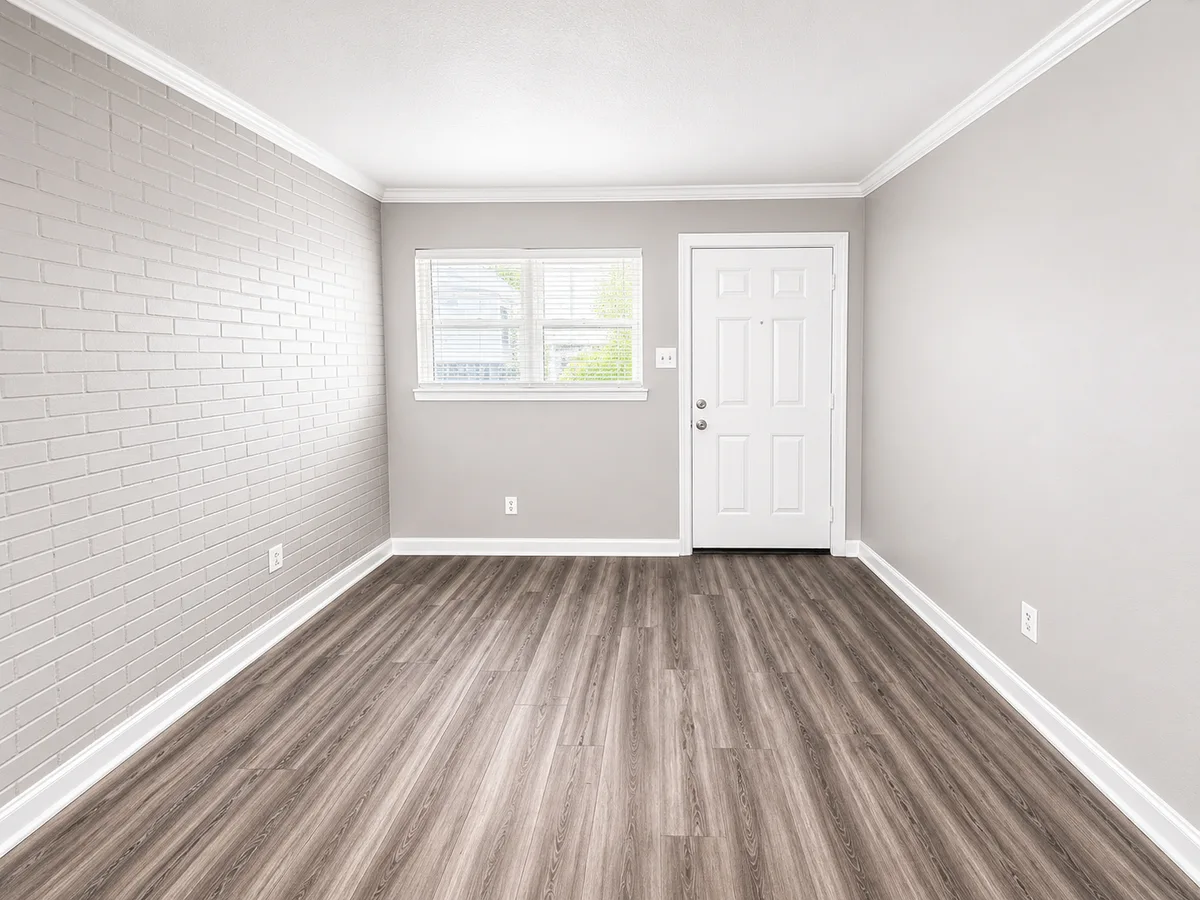 Living room with painted white brick accent wall, exterior entry door, and bright window