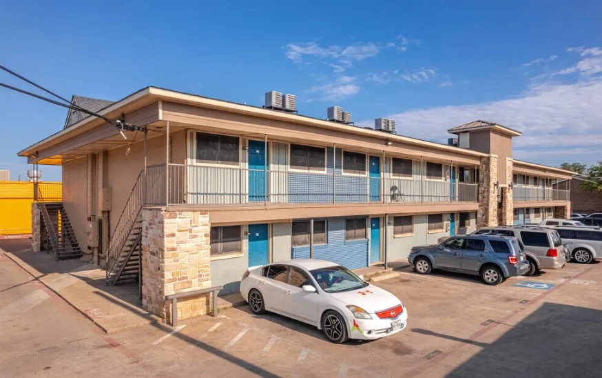 Rear building elevation with blue unit doors and striped surface parking alongside