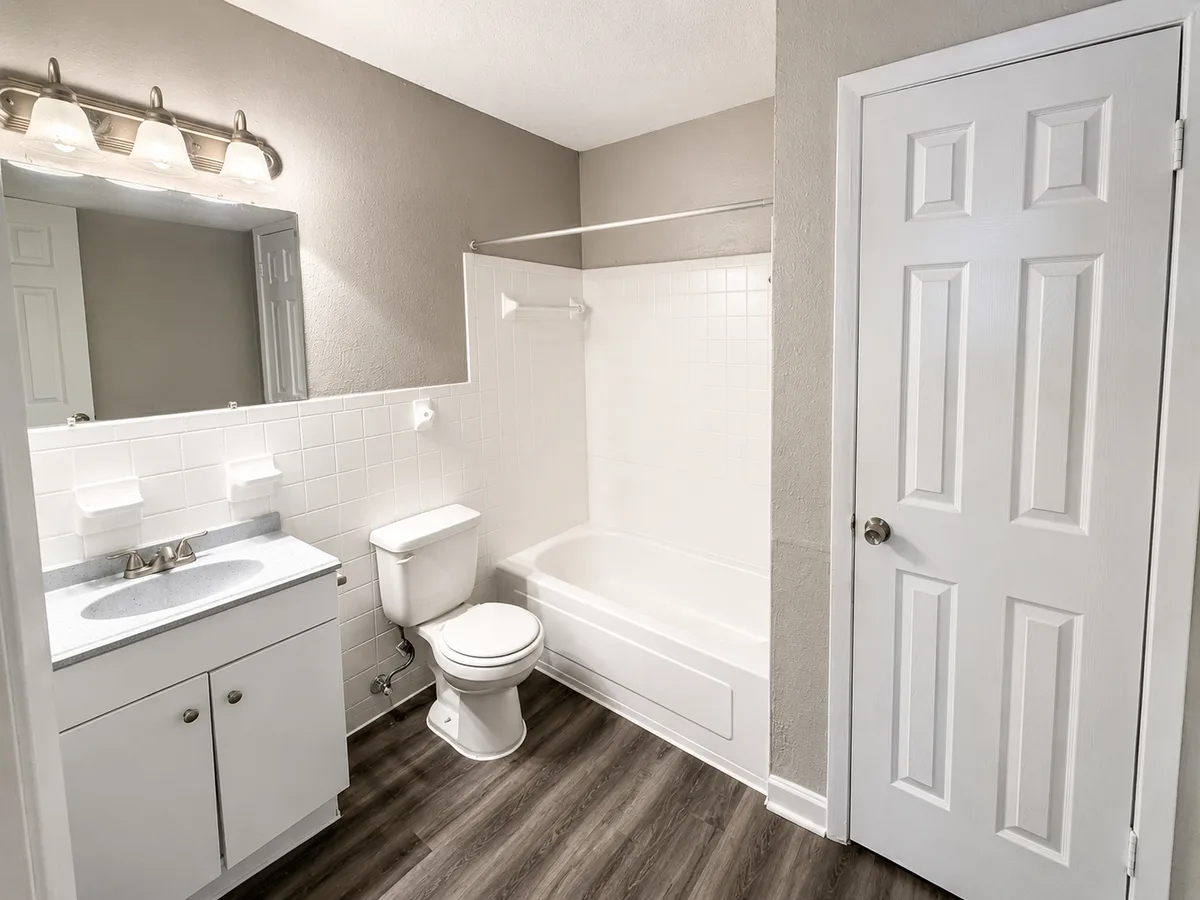 Bathroom with white subway-tile tub surround, single vanity, and framed mirror