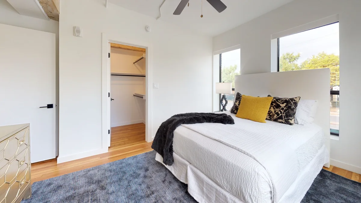 Bedroom with a walk-in closet visible through the doorway and a city-facing window