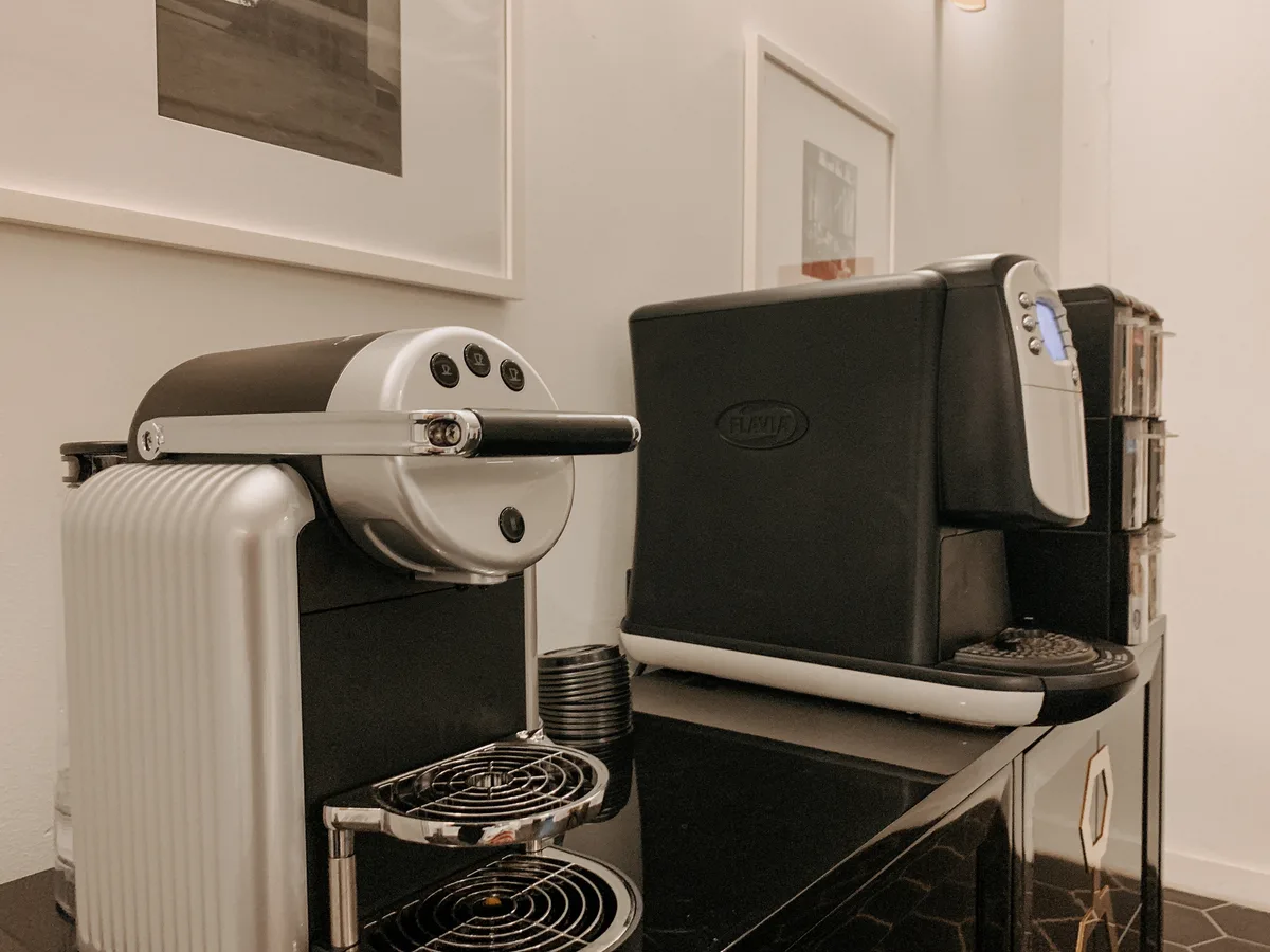 Resident coffee bar with espresso and specialty coffee machines on a black hex-tiled cabinet