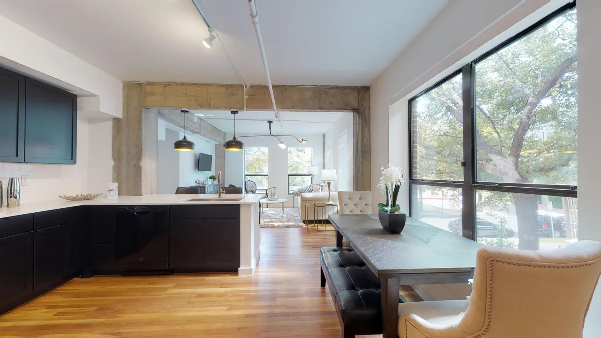 Dining area with a table for four beside a large window overlooking the tree-lined street