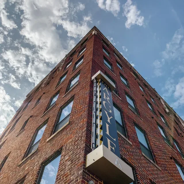 Historic red-brick high-rise seen from below with the vertical Argyle marquee sign against blue sky