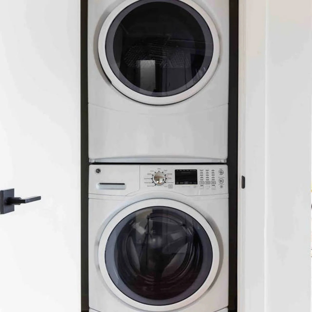 In-unit stacked washer and dryer set within a closet framed in black trim
