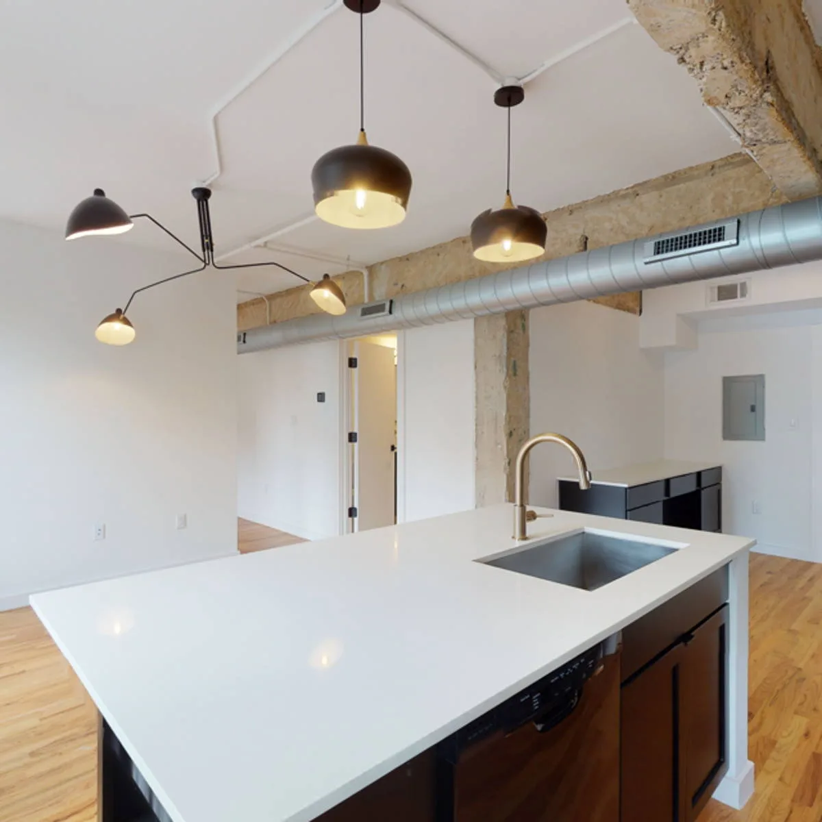 Kitchen island with quartz counter and pendant lighting below an exposed concrete column and ductwork