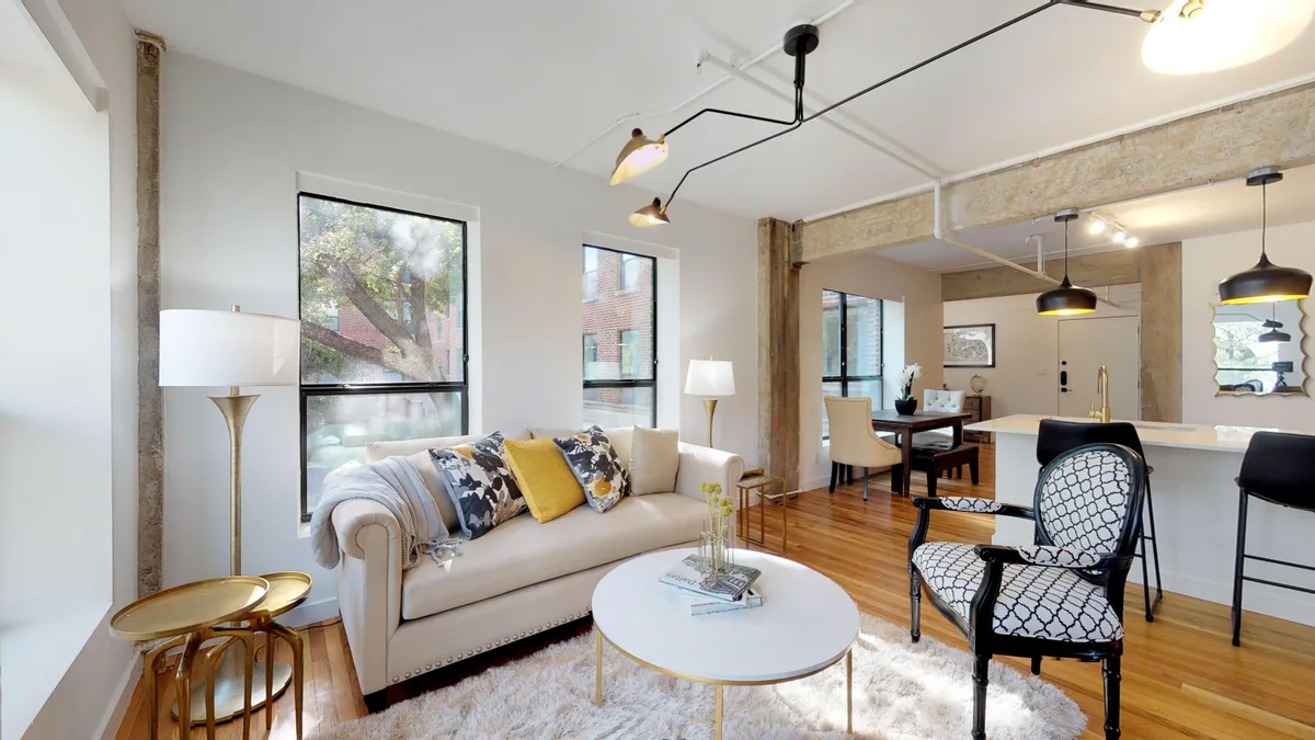 Open living room with sofa and armchairs flowing into the dining and kitchen area