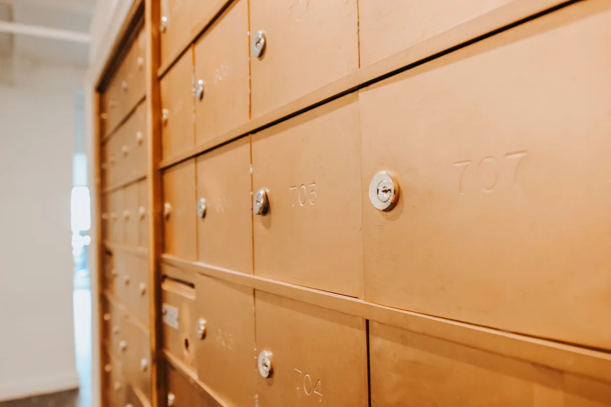 Rows of brass resident mailboxes with engraved unit numbers in the mail room