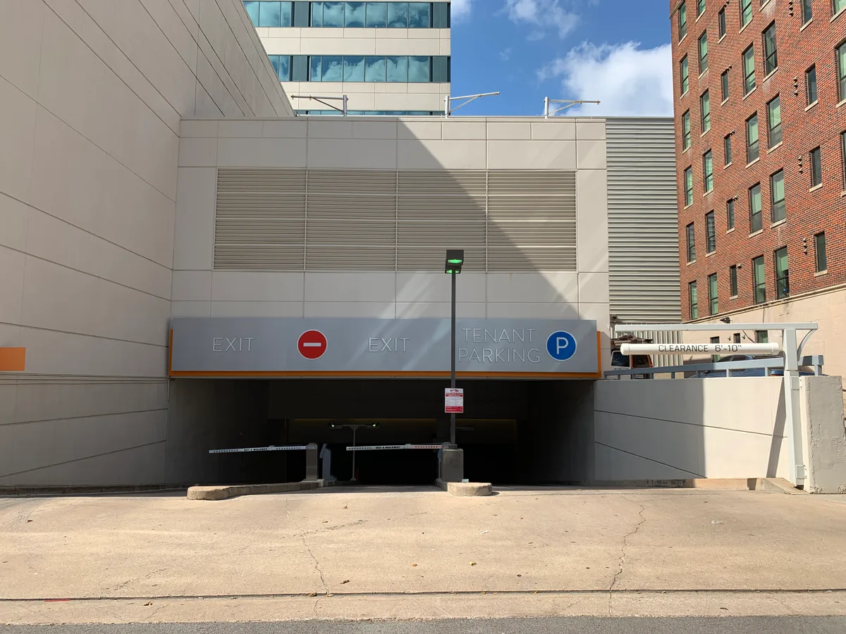 Entrance to the secured tenant parking garage marked with signage beneath adjacent downtown buildings