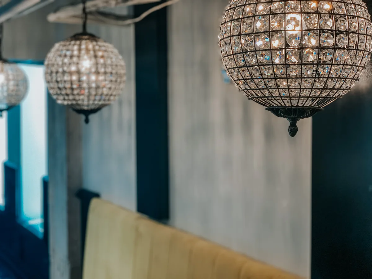 Crystal globe chandeliers glowing above velvet seating in the intimate speakeasy lounge