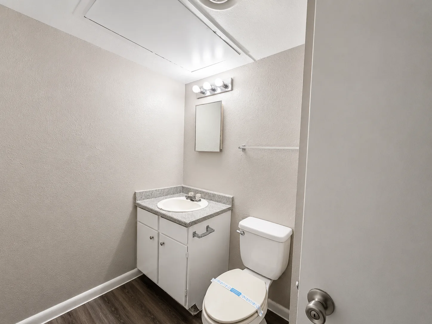 B1 half bath with a speckled-top vanity, framed mirror and toilet — no tub or shower